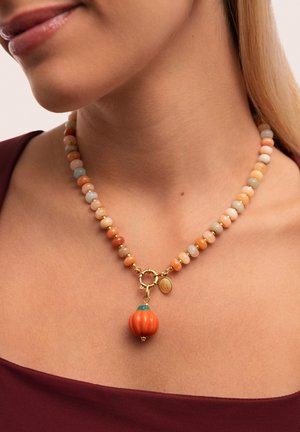 Collar de cuentas con piedras en tonos pastel, un charm de calabaza naranja y herrajes dorados con un pequeño colgante decorativo.