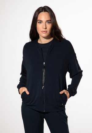 Marinefarbener Reißverschluss-Pullover mit lockerer Passform, ausgestattet mit zwei Fronttaschen und einer Kordelzugverschlus, aus weichem, dehnbarem Stoff hergestellt.