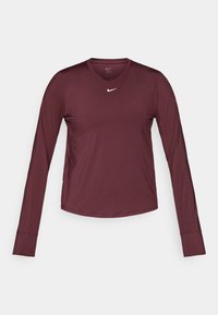 Burgundi hosszú ujjú sportpóló kerek nyakkal és fehér Nike swoosh logóval a mellen. Simás textúra, formázott kialakítás.
