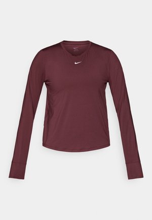 Burgundijas garās piedurknes sporta krekliņš ar apaļu kaklu un baltu Nike swoosh logotipu uz krūtīm. Gluda tekstūra, cieši pieguļošs dizains.