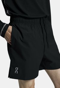 Sorte athletic shorts med elastisk talje, snøre detaljer og sidelommer, med et lille logo på venstre ben.