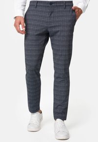 Herre navy rutete bukser med slim fit, med en strukturert tekstur, subtile blå og hvite linjer, og klassiske lommer. Brukt med hvite sneakers.