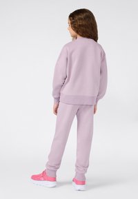 Conjunto de sudadera y pantalones en color lila, hecho de una tela suave, con puños acanalados y un corte relajado. Combinado con zapatillas deportivas rosas con suela blanca.