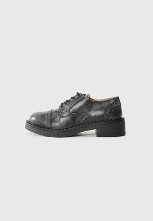 Scarpa da donna in pelle nera, con punta arrotondata, design con lacci, suola nera spessa e dettagli di cucitura decorativa lungo la parte superiore.