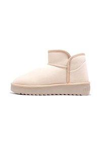 Botas de tobillo beige hechas de suave ante, con puntera redondeada, un ajuste ceñido alrededor del tobillo y suela de goma texturizada con un patrón de zigzag.