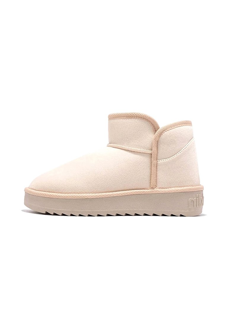 Botas de tobillo beige hechas de suave ante, con puntera redondeada, un ajuste ceñido alrededor del tobillo y suela de goma texturizada con un patrón de zigzag.