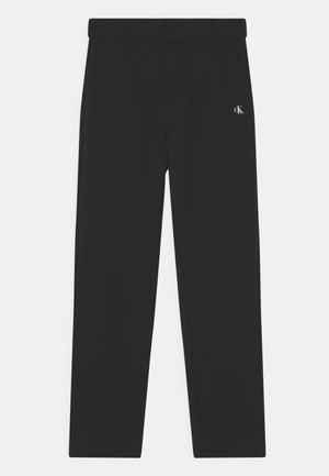Pantalon noir droit avec taille élastique et petit logo blanc Calvin Klein sur la partie supérieure de la cuisse gauche.