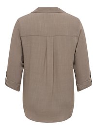 Achteraanzicht van een beige shirt met lange mouwen en kraag, een plooi in het midden van de rug, met opgerolde mouwen die zijn vastgezet met knooplusjes.