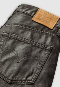 Gros plan sur la poche arrière d'un jean en denim noir avec une étiquette en cuir Levi Strauss & Co. à la taille.