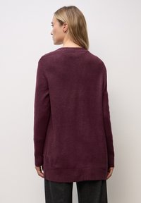 Sweater burdeos de manga larga con un corte relajado, dobladillo acanalado y una textura sutil. Presenta un escote de barco y llega hasta la altura de la cadera.