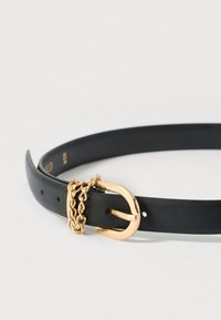 Μαύρη δερμάτινη ζώνη με αγκράφα από μέταλλο σε χρυσαφί απόχρωση και διακοσμητική αλυσίδα. Διαθέτει ομαλή υφή και πολλαπλές τρύπες για προσαρμογή μεγέθους.