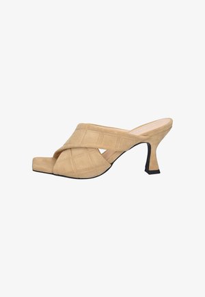 Les mules à talons hauts beige présentent un design à bandes croisées et un bout carré, avec une finition en daim texturé et un talon noir effilé.
