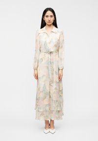 Μακρύ, ρέον φόρεμα από διάφανο ύφασμα με παστέλ λουλουδάτα σχέδια. Διαθέτει γιακά, μακριά μανίκια και δέσιμο στη μέση.