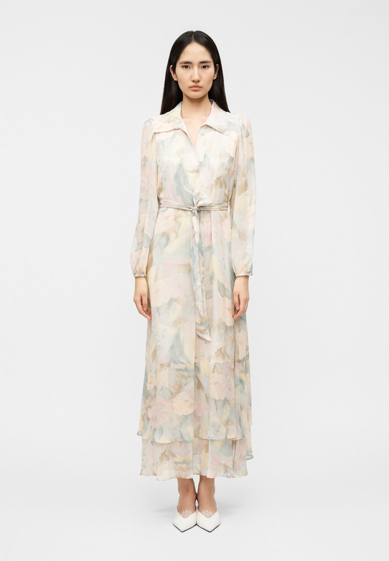 Μακρύ, ρέον φόρεμα από διάφανο ύφασμα με παστέλ λουλουδάτα σχέδια. Διαθέτει γιακά, μακριά μανίκια και δέσιμο στη μέση.