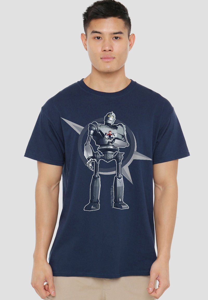Young man wearing navy blue t-shirt with large robot holding small boy design on front against light gray background.