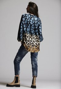 Silk blouse with blue and black animal print, gradient down to tan leopard print. Worn with distressed blue jeans and beige ankle boots.