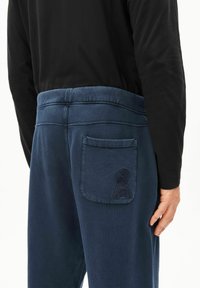 Marineblauwe joggingbroek met een elastische tailleband en een achterzak voorzien van een logo met structuurdetail. Glad stof met een ontspannen pasvorm.