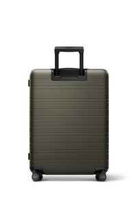 Valise rigide de couleur vert olive, dotée de rainures horizontales, d'une poignée rétractable et de quatre roues noires pour la mobilité.