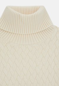 Sweter w kolorze kremowym z kołnierzem typu golf oraz fakturowanym, tkanym wzorem na korpusie. Miękka, dziana tkanina.