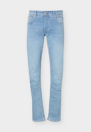 Ανοιχτό μπλε slim-fit τζιν με εμπρός κουμπί και φερμουάρ, πέντε τσέπες και θηλιές για ζώνη, σε απλό φόντο.
