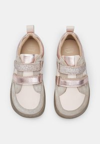 Jasnoróżowe i beżowe sneakersy z podwójnymi rzepami, zamszowymi i metalicznymi akcentami, okrągłym noskiem oraz teksturowanymi gumowymi podeszwami.
