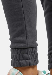 Graue Jogginghosen zeichnen sich durch ein tailliertes Design mit elastischen Bündchen an den Knöcheln aus und sind aus einem weichen, strukturierten Stoff gefertigt.
