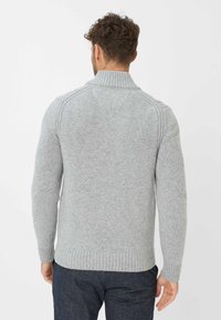 Grauer Strickpullover mit einem gerippten Kragen und Saum, mit Raglanärmeln und einer strukturierten Oberfläche des Stoffes, von hinten betrachtet.