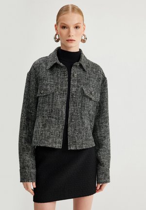 Zwart-wit gebloemde cropped jack met kraag, knoopsluiting, twee borstzakken en lange mouwen. Geurweven stofafwerking.