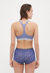 Lila sportmelltartó racerback dizájnnal, fehér logós pánttal. Magas derekú fehérnemű sötétkék színben, világos absztrakt mintával.