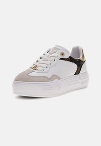Sneaker bianca con punta in suede grigia, lato con motivo nero e dettagli dorati. Presenta un design con lacci e suola bianca spessa. Logo del marchio visibile.