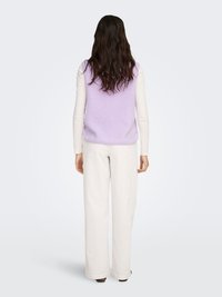 Chaleco de forro polar lila claro con acabado texturizado, presenta un escote redondeado y diseño sin mangas, combinado con pantalones blancos de pierna ancha.