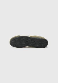 Grønn semsket sneakersåle med en teksturert svart gummi yttersåle. Har en hvit mellomsåle og et karakteristisk mønster for grep.