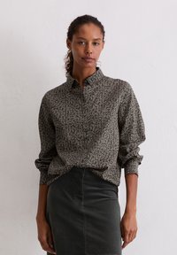 Bloemenprint overhemd in donkergrijs met witte accenten, voorzien van een kraag, lange mouwen en een ontspannen pasvorm. Gecombineerd met een donkere rok.