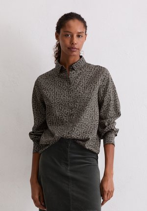 Koszula na guziki w ciemnoszarym kolorze z białymi akcentami, z wzorem kwiatowym, kołnierzykiem, długimi rękawami i luźnym krojem. Do zestawu ciemna spódnica.