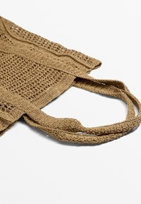 Geflochtene Tragetasche aus natürlichen Fasern, mit einem strukturierten Muster, zwei stabilen Griffen und einer sandfarbenen Nuance für ein funktionales Design.