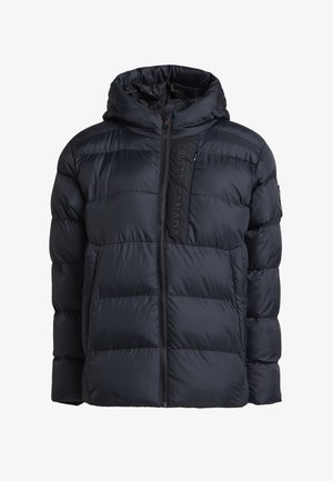 Tamsiai mėlyna pūkinė striukė su užtrauktuku priekyje, paminkštintomis dalimis ir kapišonu. Papuošta vertikaliu logotipo akcentu ant užtrauktuko panelės.