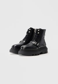 Black leather ankle boots with a rounded toe, lace-up front, side zipper, chunky sole, and decorative silver hardware accents.