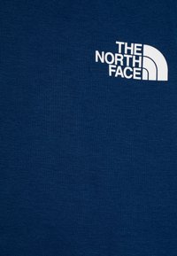 Mornarsko modra majica z dolgimi rokavi, izdelana iz bombažne mešanice, s papirnatim logotipom "The North Face" na zgornji levi strani.