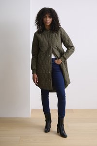 Olivgrön, vadderad lång kappa med knäppning fram och ribbade ärmar, tillsammans med mörkblå skinny jeans och svarta ankelboots.