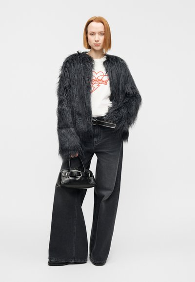 Μαύρο μπουφάν από συνθετική γούνα με υφή, λευκό μπλουζάκι με κόκκινο γραφικό, ψηλόμεσο σκούρο τζιν και μικρή μαύρη τσάντα με ασημί εξαρτήματα.
