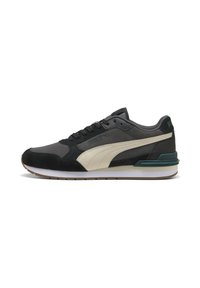 Niedrig geschnittenen Puma Sneaker in Schwarz und Grau mit einem weißen Seitenstreifen, schwarzen Schnürsenkeln und einer weißen Sohle mit braunem Profil.