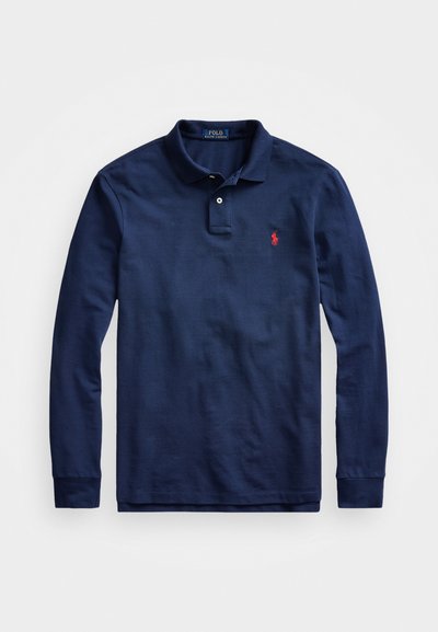 Polo de manga longa azul marinho feito de algodão, com uma abertura de dois botões, punhos canelados e um pequeno logótipo vermelho no lado esquerdo do peito.