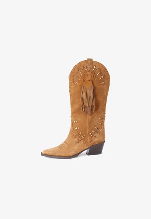 Lichtbruine suède cowboylaars met spitse neus, halfhoge hak, decoratief stiksel, gouden studs en lange kwast aan de zijkant.