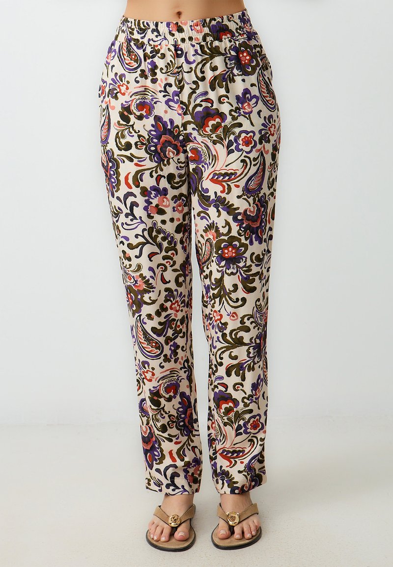 Pantalons fleuris légers avec taille élastique sur fond crème, présentant des motifs paisley complexes en violet, vert et rose, et une coupe décontractée.