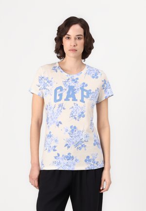 Kottongen T-skjorte med blomstertrykk i blått på en lys beige bakgrunn, med rund halslinning og "GAP"-logo i blått foran.