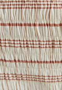 Tessuto leggero con un design testurizzato e arricciato. Presenta righe alternative in morbidi colori beige e ruggine. Superficie liscia con una lucentezza sottile.