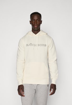 Cream hoodie with a front pocket and drawstring, featuring "BJÖRN BORG" logo in black. Soft fabric with a relaxed fit. Grey sweatpants.