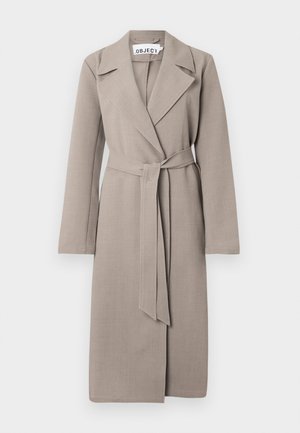 Trench-coat long ceinturé de couleur marron clair avec larges revers et manches longues, présenté sur un fond blanc.