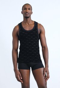 Μαύρη αμάνικη μπλούζα με υφή που διαθέτει επαναλαμβανόμενο σχέδιο. Απαλή ύφανση, εφαρμοστή γραμμή και λεπτομέρειες σε μαύρο χρώμα.