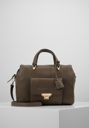 Sac à main en cuir marron foncé avec deux poignées, poche avant à rabat avec fermoir doré et bandoulière amovible sur une surface blanche.